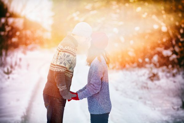 زن و شوهر جوان در عشق نگه داشتن دست در فضای باز در زمستان در غروب آفتاب