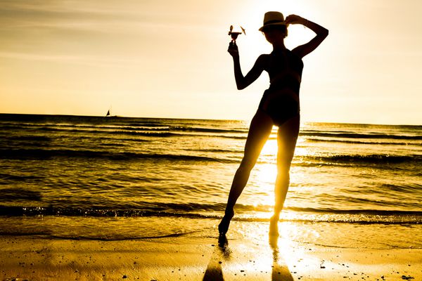 زن جوان با ساحل در مناطق گرمسیری در پس زمینه غروب آفتاب
