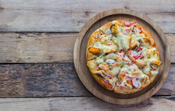پیتزا دریایی تازه پخته شده در سطح میز چوبی