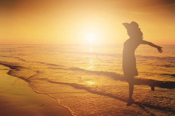 زن مبارک پریدن در ساحل دریا شبح غروب آفتاب