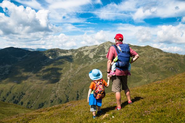 پدر پسر و کودک در حامل تماشای دید کوه در حالی که پیاده روی در Alps تابستان آستری