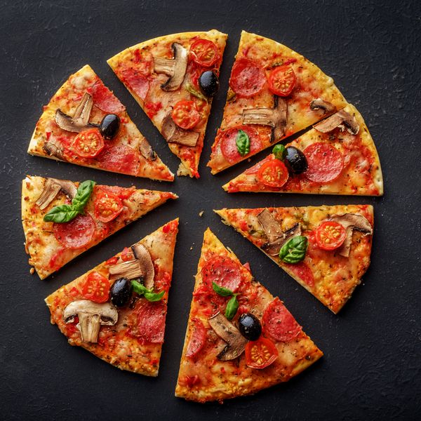 پیتزا تازه با قارچ و نخود فرنگی را در یک زمینه تیره بریزید نمای بالا پیتزا روی میز سیاه