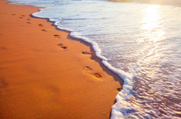 ساحل موج و رد پا در زمان غروب آفتاب
