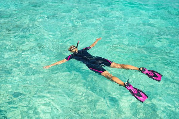 زن snorkeling در آب های گرمسیری روشن در مقابل جزیره عجیب و غریب