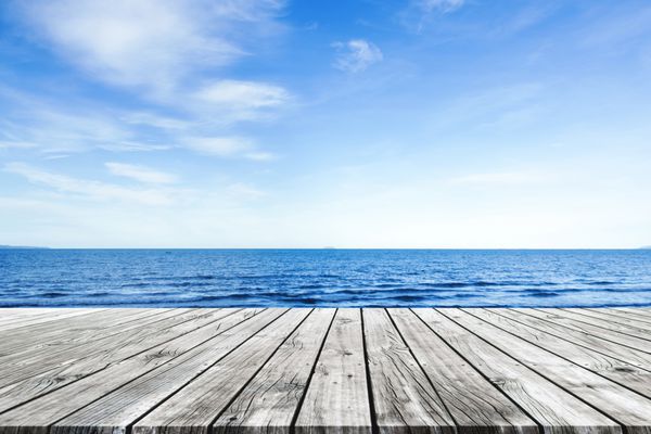 اسکله چوبی با پس زمینه آبی دریا و آسمان