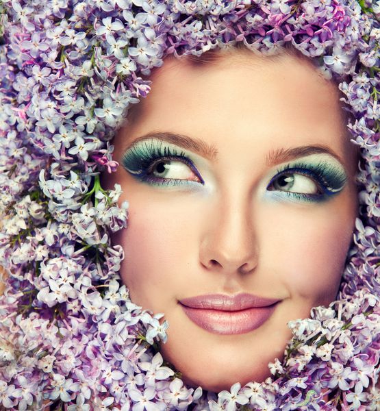 مدل دختر زیبا در گل های یاس بنفش در اطراف صورت تصویر خنده دار از بهار و تابستان تازه آرایش لوازم آرایشی و زیبایی