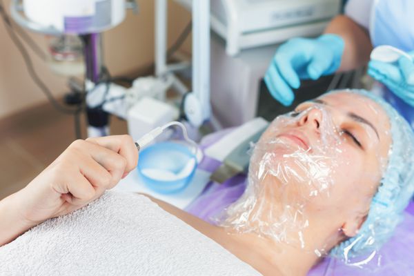 زن در سالن اسپا درمان پوستی را دریافت می کند جوان سازی صورت تمیز کردن سونوگرافی صورت ایجاد انسداد برای اتمی سازی بهتر لایه بالایی پوست