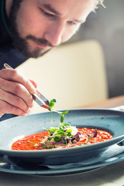 آشپز در رستوران یا هتل آشپزخانه تنها دست او روی گیاه میکرو و تهیه سوپ گوجه فرنگی کار می کند