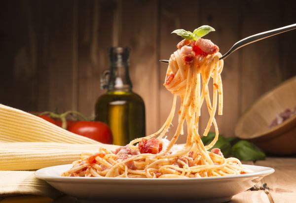 اسپاگتی با سس amatriciana در ظرف بر روی میز چوبی