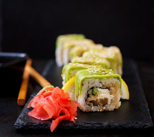 غذا های سنتی ژاپنی سوشی رول و سس روی پس زمینه سیاه
