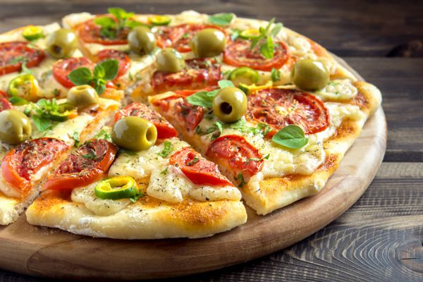 پیتزا سبزیجات خانگی با گوجه فرنگی زیتون سبز فلفل ریحان پونه کوهی و پنیر روی میز چوبی با رونوشت فضای