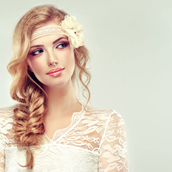 دختر مدل زیبا در لباس سفید با یک خوک و گل بدون درز در سر او عروس در لباس عروسی به سبک گاه به گاه و یا boho با braid مدل موی