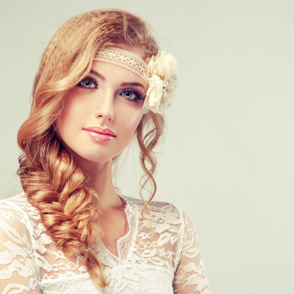 دختر مدل زیبا در لباس سفید با یک خوک و گل بدون درز در سر او عروس در لباس عروسی به سبک گاه به گاه و یا boho با braid مدل موی