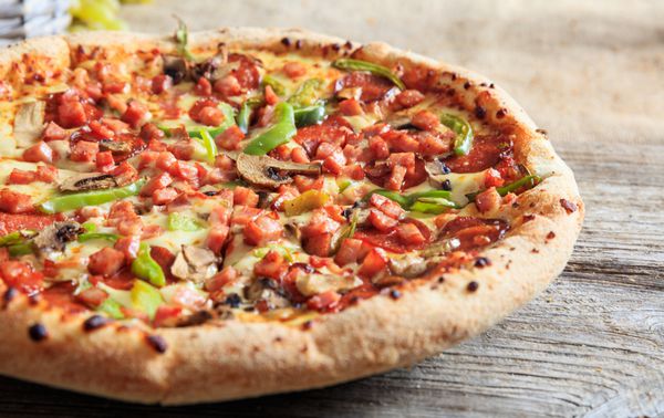 پیتزا بر روی یک سطح چوبی