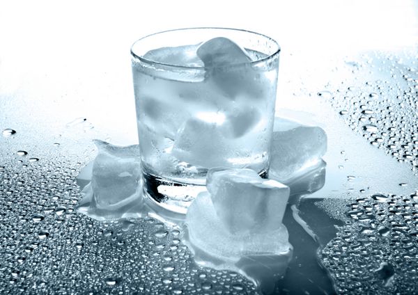 شیشه ای با نوشیدنی و یخ در یک پس زمینه سفید