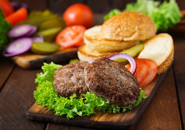 مواد لازم برای ساندویچ برگر همبرگر با گوشت گاو ترشی گوجه فرنگی و پیاز قرمز در زمینه های چوبی