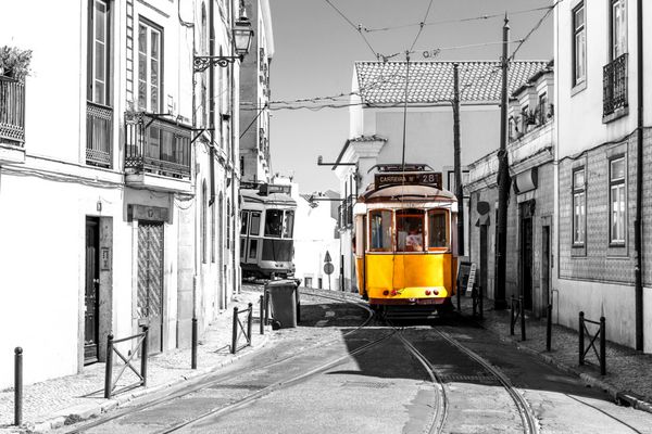 تراموا زرد در خیابان های قدیمی لیسبون پرتغال جاذبه های گردشگری و مقصد تصویر سیاه و سفید با یک تراموا رنگی