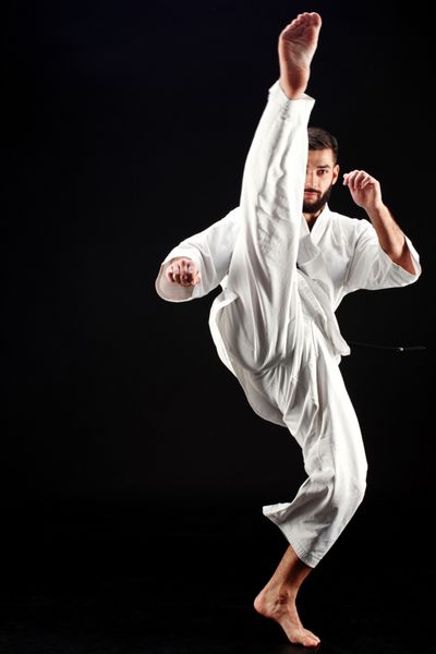 مرد کاراته در یک کیمونو در پس زمینه سیاه پوست قرار دارد