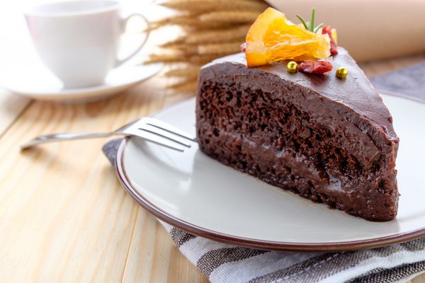 کیک شکلاتی خوشمزه در بشقاب روی زمینه چوبی