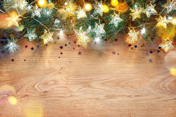 پس زمینه تعطیلات کریسمس صنوبر تزئین شده با چراغ روی تخته چوبی کریسمس مبارک و مبارک سال نو نمای بالا