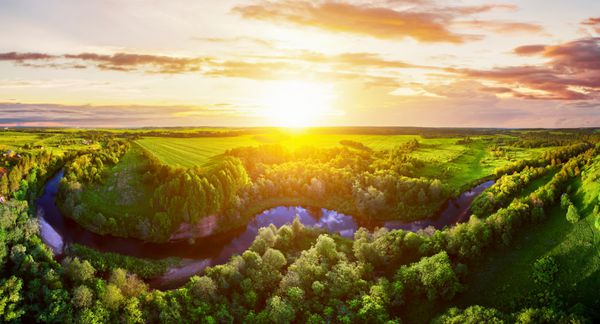 غروب خورشید در منظره طبیعت پانورامای هوایی رودخانه آبی آرام در جنگل و حوزه های غروب آفتاب منظره طبیعت تابستان آسمان ابری دراماتیک مشاهده چشم انداز جنگل طبیعت