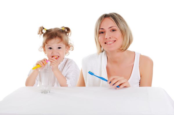مادر جوان و دختر جوانش دندان های خود را بر روی زمینه سفید قرار می دهند