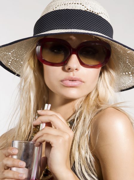 دختر با کلاه تابستانی و عینک آفتابی نما و نوشیدن