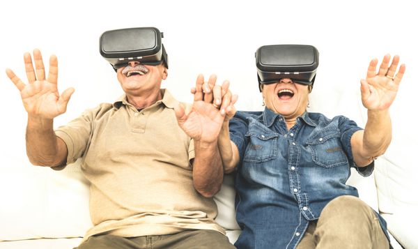 زن و شوهر بالغ ارشد لذت داشتن با هدست واقعیت مجازی نشسته روی مبل افراد بازنشسته مبارک با استفاده از عینک های مدرن عینک آفتابی روند جدید و مفهوم فناوری و سالخوردهای فعال خنده دار