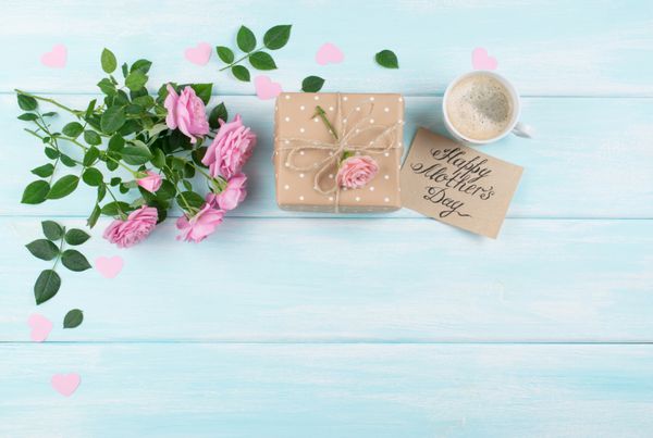 گل های صورتی با کارت پستال کاغذی فنجان قهوه و جعبه هدیه ای برای روز مادران در زمینه پس زمینه تخته های کمربند چوبی فضای کپی کنید نمای بالا طراحی تخت