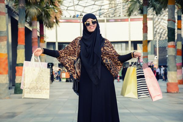 بعد از خرید روز نزدیک دختر جوان عربی حمل کیسه های خرید در حالی که راه رفتن در خیابان پوشیدن ابایا و حجاب