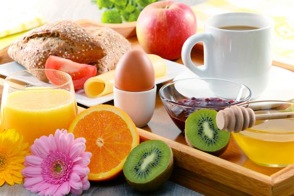 صبحانه در سینی با قهوه آب پرتقال تخم مرغ رول و عسل سرو می شود رژیم غذایی متعادل