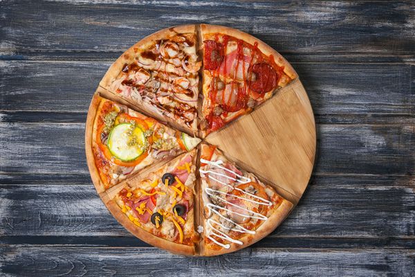قطعات پیتزا را با طعم های مختلف بدون یک قطعه بر روی میز چوبی برش دهید