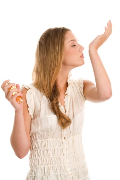 زن جوان عطر زننده در مچ دست بر روی زمینه سفید است