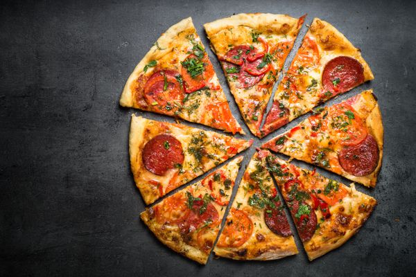 پیتزا سنتی ایتالیایی با سالامی پنیر سبزیجات گوجه فرنگی نمایش بالا در میز سنگی تیره پس زمینه ایتالیایی مواد غذایی