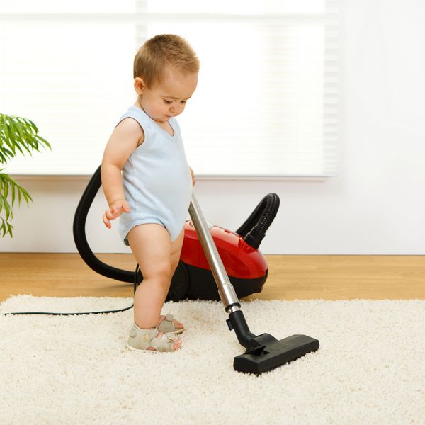 پسر بچه تمیز کردن فرش با جارو برقی