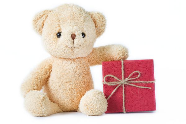 عروسک خرس با جعبه هدیه قرمز در پس زمینه سفید جدا شده است