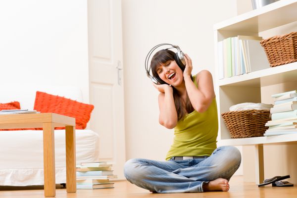 دختر نوجوان خانه را آرام کنید به موسیقی با آواز هدفون گوش می دهید
