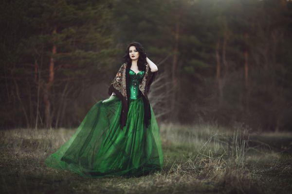 یک دختر در یک لباس سبز و یک روسری از طریق جنگل می گذرد ArtPhoto