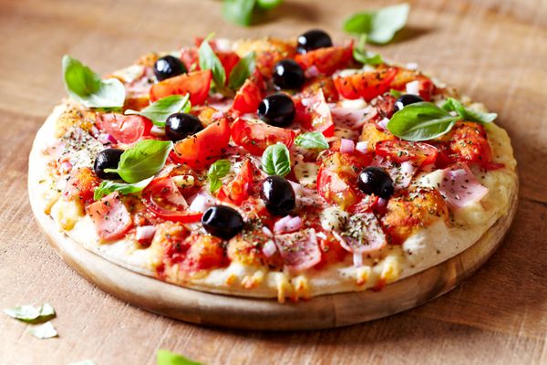پیتزا با ژامبون زیتون های سیاه گوجه فرنگی گیلاس ادویه جات ترشی جات و ریحان تازه پیتزای ایتالیایی غذای خانگی مفهوم غذا خوشمزه و شاداب پس زمینه های چوبی قهوه ای