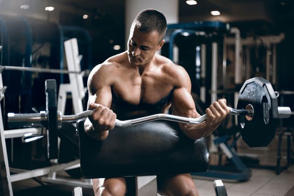 مرد بدنساز عضلانی تمرینات با دمبل در ورزشگاه انجام می دهد