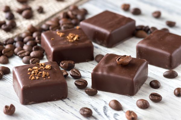 Chocolate sweets with coffee beans on a white wooden table Candies bird