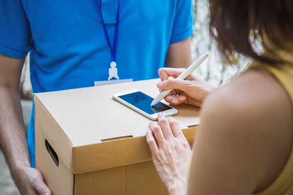 زن آسیایی با اضافه کردن علامت امضا در تلفن هوشمند پس از پذیرش جعبه دریافت از مرد تحویل زن در جعبه وارد شوید دریافت مفهوم تحویل