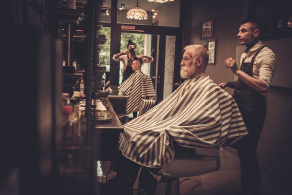 مرد ارشد بازدید کننده از مدل موهای مردانه در فروشگاه سلمانی