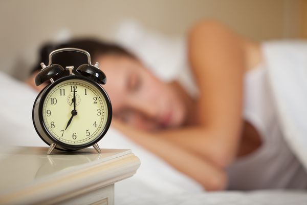 زن جوان خواب و ساعت زنگ دار در اتاق خواب در خانه
