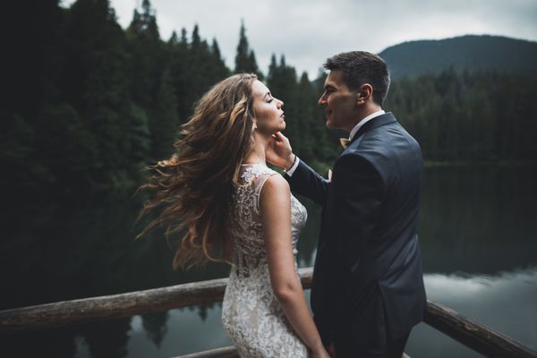 زن و شوهر عروسی زیبا بوسیدن و در آغوش نزدیک کوه با دید کامل است