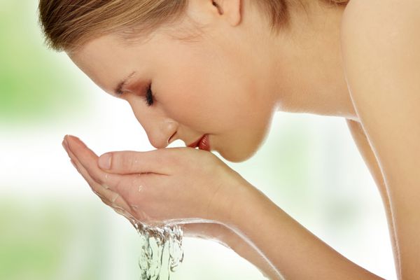 زن جوان شستن صورت خود را با آب پاک