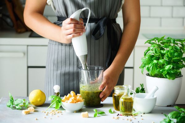 زن با استفاده از جارو برقی برای ساخت پاستو طراحی داخلی آشپزخانه آشپزخانه فضای کپی کنید گیاهخواری مفهوم سبک زندگی غذا خوردن