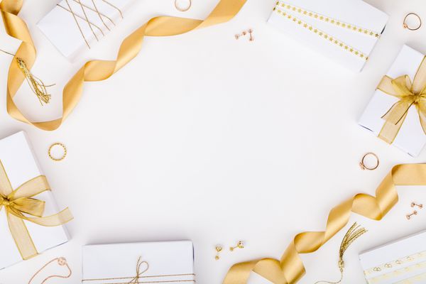 طلا و جواهر طلایی و جعبه هدیه در پس زمینه سفید با فضای کپی برای متن مفهوم مد و خرید عروسی ازدواج یا ترکیب تولد تختخواب نمای بالا