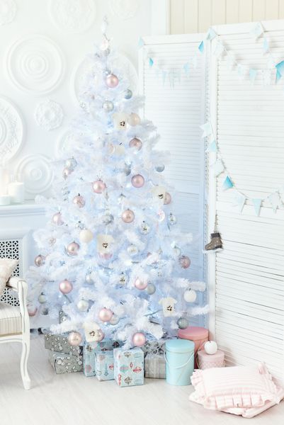 درخت هریسمس با توپ های رنگارنگ و جعبه های هدیه بر روی دیوار سفید