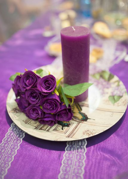 عروسی جشن دکوراسیون گل و گیاه گل های بنفش و شمع بر روی صفحه زیور آلات